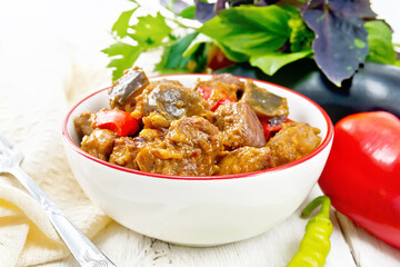 Meat with eggplant and pepper in bowl on light board