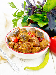 Meat with eggplant and pepper in bowl on wooden board