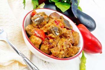 Meat with eggplant and pepper in bowl on light table