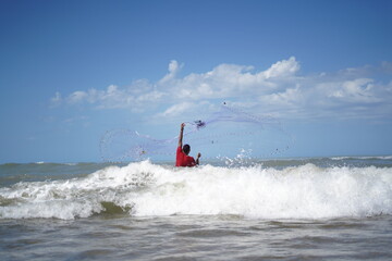 Obraz premium Man fishing between waves