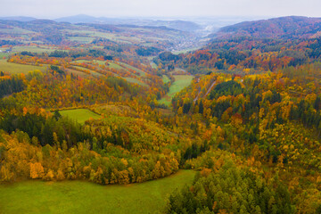 Scenic autumn country landscape with colorful trees on hillsides and empty fields..
