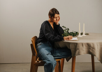 Tired woman looking down at the notepad on a round table, writing