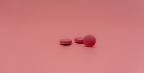 Selective focus on round pink tablet pill on pink background. Pharmacy horizontal web banner....