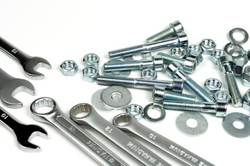 several silver color metal bolts with nuts and wrenches on a white background. close-up and copy space