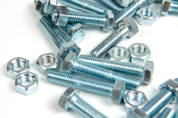 several silver metal bolts with nuts on a white background. close-up and copy space