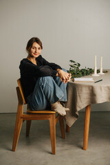 Smiling tired woman sitting with legs up on a chair next to a round table