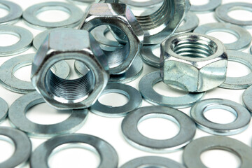 several metal washers and large nuts of silver color on a white background. close-up