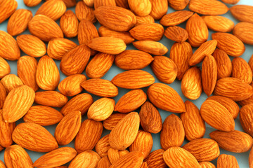 Raw and peeled almonds placed abruptly on a blue background