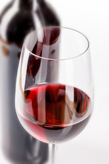 glass of red wine and bottle on white background