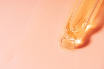 Pipette filled with oil close-up on pink background.