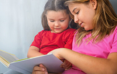 Teenager helps the child to read a book