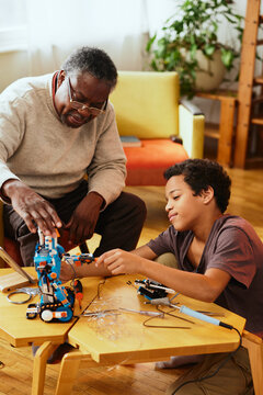 A Grandad And Grandson Making A Robot Together At Home. Education In Robotics And Electronics.