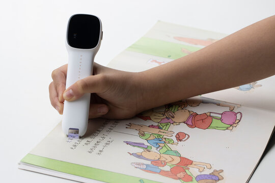 Portland, OR, USA - Apr 8, 2021: A child reads a Chinese picture book using an Alpha Egg Q3 reader and translator pen, which scans the text and reads it out.