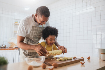 Happy Smiling African American Father and son Cooking and kneading dough, Black African male and...