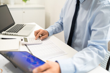 Working Man Conept The office man holding tablet and pressing the calculator while sitting in the office