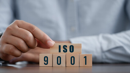 Businessman place the wooden cubes with ISO 9001 standards quality control concept, assurance...