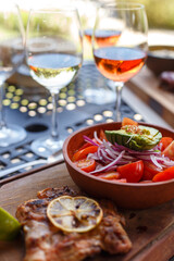 Plate with vegetable salad and glasses of wine on the table