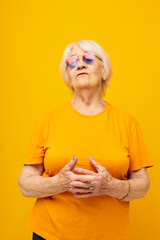 Portrait of an old friendly woman in a yellow t-shirt posing isolated background