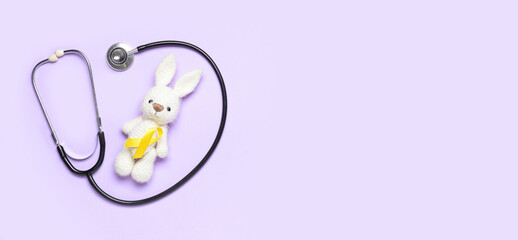 Bunny toy and golden awareness ribbon with stethoscope on color background with space for text. International Childhood Cancer Day