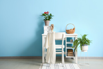 Workplace with Anthurium flower, wooden hand holding eyeglasses and basket near color wall