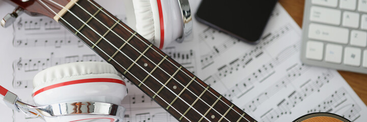 Guitar headphones and musical notes on table closeup