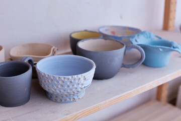 Empty handmade tableware. ceramic cups on the shelf. Handmade work. Glaze of blue color on clay.