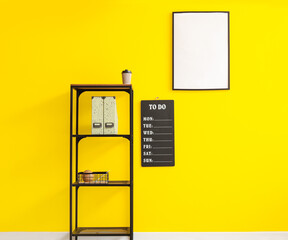 Shelf unit with folders, board with to do list and blank frame on color wall
