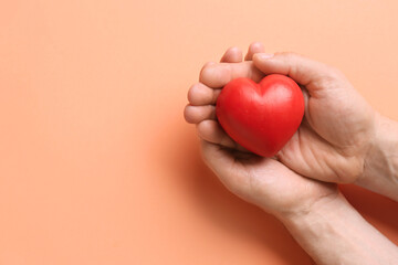 Man holding red heart on color background, closeup. Donation concept