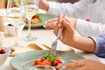 Obraz na płótnie Canvas Women eating delicious Pasta Puttanesca at table in restaurant