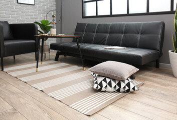 Interior of living room with modern furniture near grey brick wall