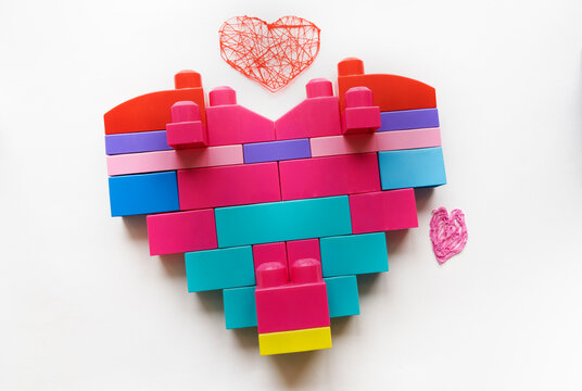 A heart made of pink details of a large constructor on a white background. Valentine's Day greeting card. The child loves his mother