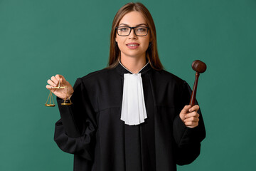 Young female judge with gavel and scales of justice on color background