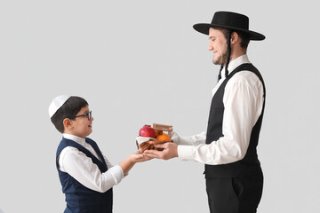 Jewish man and boy with fruits in basket on grey background. Purim celebration