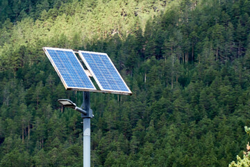 lamppost with a solar battery against forest covered mountain