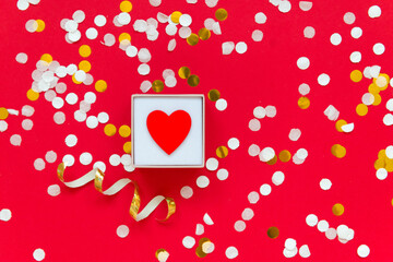 little red heart in box on red background with confetti