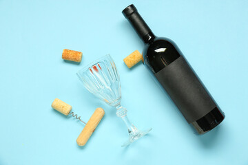 Bottle of wine, corks, glass and opener on blue background