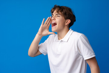 Teen boy making loud announcement against blue background.