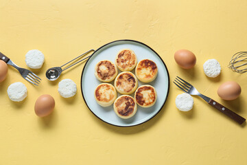 Plate with tasty cottage cheese pancakes and eggs on yellow background