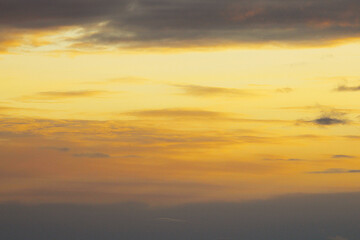 Sun below the horizon and clouds in the fiery dramatic orange sky at sunset or dawn backlit by the sun. Place for text and design, wallpaper and background