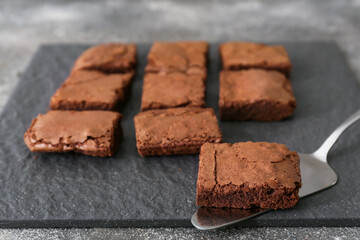 Board with pieces of tasty chocolate brownie on table