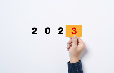 Hand holding yellow paper with number three for preparation new business year from 2022 to 2023...