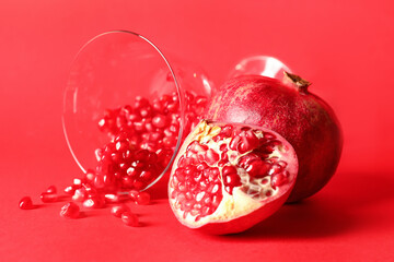 Glass with ripe delicious pomegranate on red background