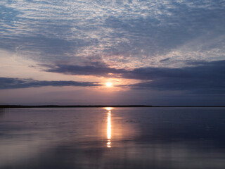 View of clouds reflected in the smooth water of the lake at sunset.