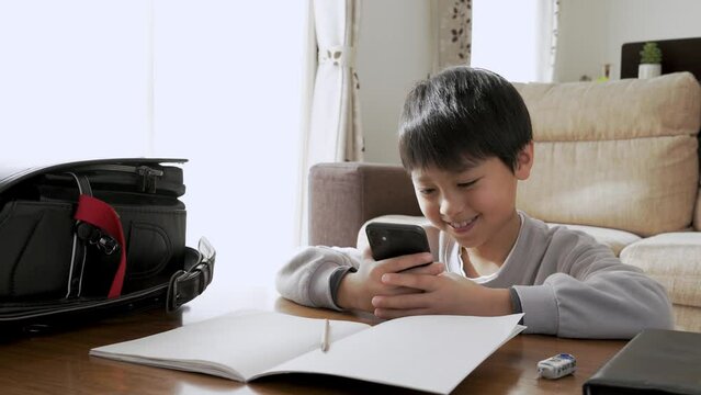 宿題をやらないでスマホを見る小学生の男の子