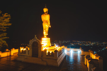 Fototapeta na wymiar Golden Buddha statue in the nighttime at Wat Phra That Khao Noi, or Phrathat Khao Noi temple, is the top attraction with a fantastic view of Nan province, Thailand