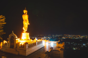 Golden Buddha statue in the nighttime at Wat Phra That Khao Noi, or Phrathat Khao Noi temple, is the top attraction with a fantastic view of Nan province, Thailand