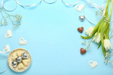 Fototapeta na wymiar Composition with tasty heart-shaped candies and flowers for Valentine's Day celebration on blue background