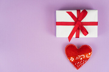 Valentines Day concept with copy space. Red textile heart and goft box on purple papper background