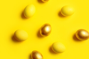Yellow and golden Easter eggs on color background