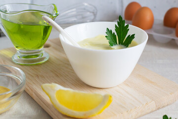 Homemade mayonnaise in a white bowl with parsley leaf and olive oil. The concept homemade food....